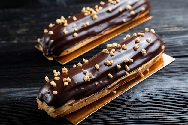 Postre tradicional francés. Eclair con chocolate. Fondo oscuro