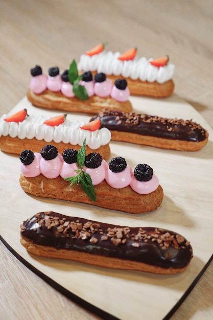 Postre tradicional francés Eclair con crema de chocolate glaseado fresas cereza menta