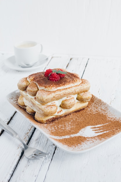 Postre tradicional italiano tiramisú casero con frambuesas frescas