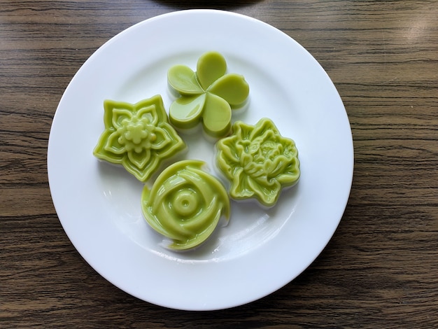 Postre tradicional tailandés jalea de leche de coco flores sobre fondo de madera