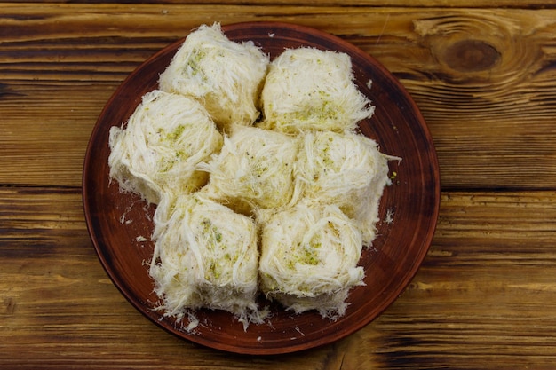 Foto postre tradicional turco pismaniye con pistachos sobre mesa de madera