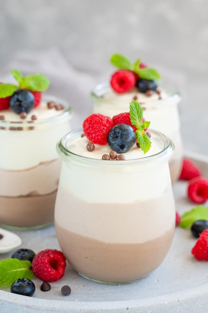 Postre tres chocolates en un frasco de vidrio con arándanos frescos, frambuesas y moras encima