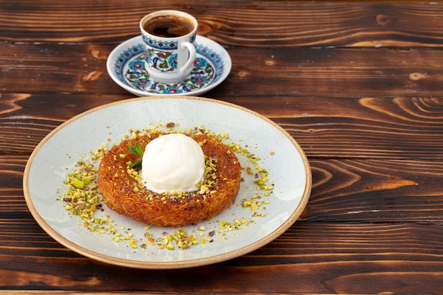 Foto postre turco kunefe con bola de helado sobre fondo de madera