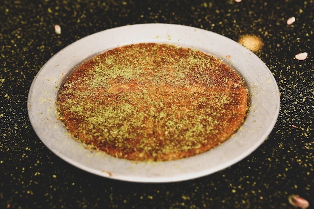Foto postre turco kunefe kunafa kadayif con polvo de pistacho y queso caliente comido un dulce