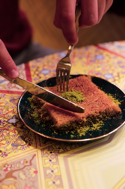 Postre turco kunefe, kunafa, kadayif con polvo de pistacho y queso caliente comido un dulce