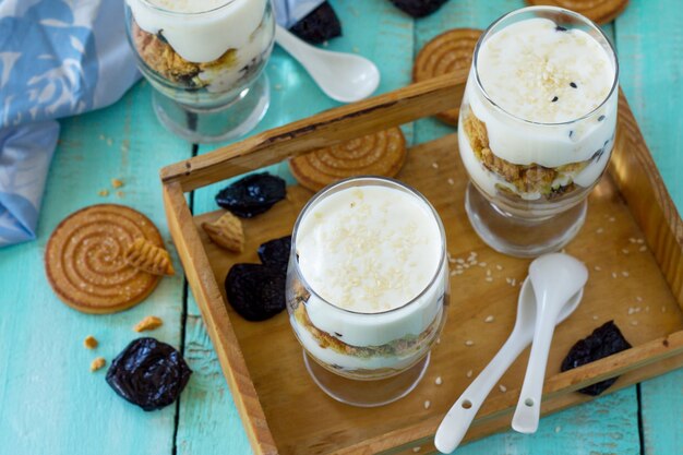 Postre vegano con crema batida nueces avena ciruelas y sésamo en vasos de vidrio