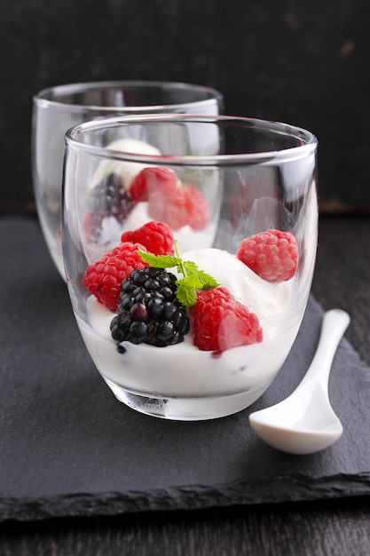 Postre de verano con bayas y helado en vasos sobre un fondo negro