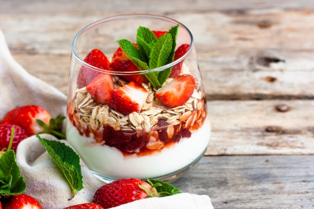 Postre de yogur de fresa con granola en una mesa de madera.