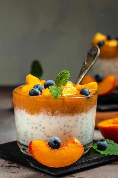 Postre de yogur con melocotones, arándanos y chía sobre un fondo oscuro Postre de frutas de desintoxicación natural concepto de dieta saludable