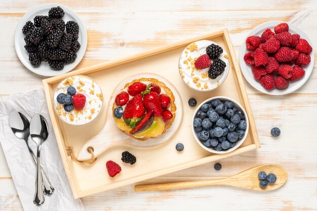 Postres dulces con bayas frescas sobre superficie de madera