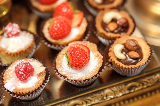 Postres gourmet en bandeja de cobre. Macarrones de vainilla, muffin de limón, tarta de frambuesas y chocolate