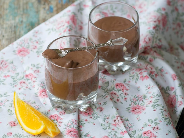 Postres de mousse de chocolate vegano con naranja en un vaso con una cuchara rebanadas frescas de naranja sobre un fondo claro Provenza Primer plano