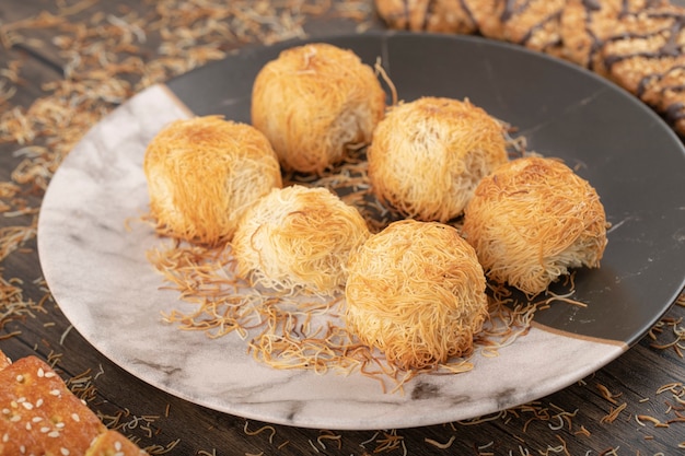 Postres turcos en un plato colocado sobre una mesa de madera.