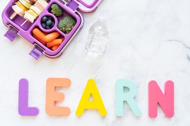 Postura plana. Almoço escolar saudável com sanduíche de kebab e legumes em caixa de bento.