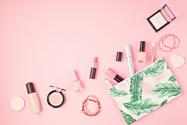 Postura plana com conjunto de cosméticos decorativos profissionais, ferramentas de maquiagem e primavera mulher, acessórios de verão, parede rosa com espaço de cópia. Blog de beleza, moda, festa, conceito de compras. Vista do topo