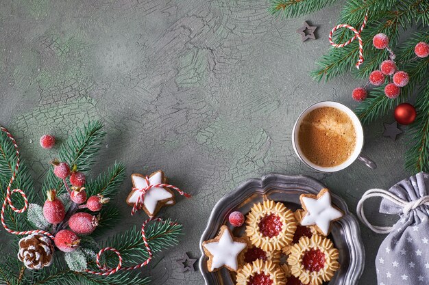 Postura plana com decorações de Natal em verde e vermelho com bagas e bugigangas foscas, café e biscoito de Natal