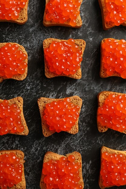 Postura plana com fatias de pão com caviar em fundo preto esfumaçado