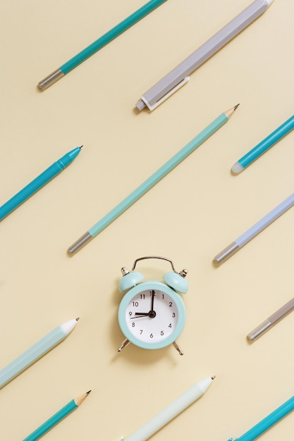 Postura plana com relógio e padrão geométrico de canetas azuis e lápis em bege Hora de ir para a escola