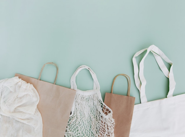 Postura plana com sacos de papel artesanal eco branco e sacos de rede em fundo verde com espaço de cópia