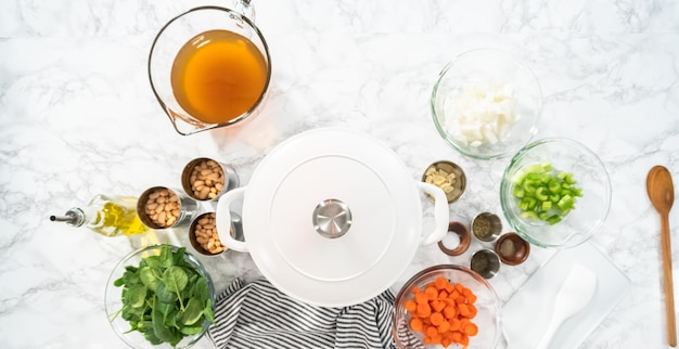 Postura plana. Cozinhar sopa de feijão branco vegetariano em forno holandês de ferro fundido.