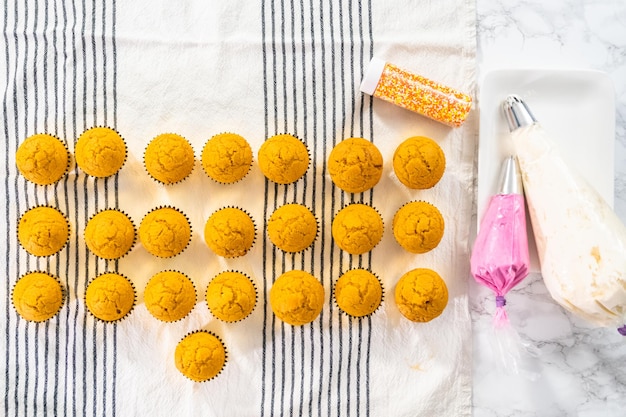 Foto postura plana. cupcake de especiarias de abóbora recém-assados refrigerando na toalha de cozinha.