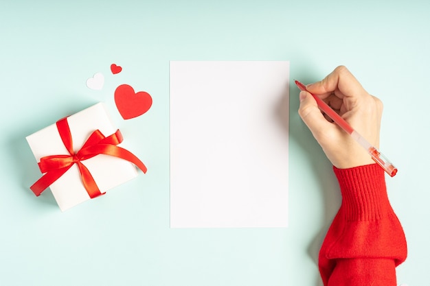 Postura plana da mão de mulheres com carta em branco e presente de dia dos namorados.