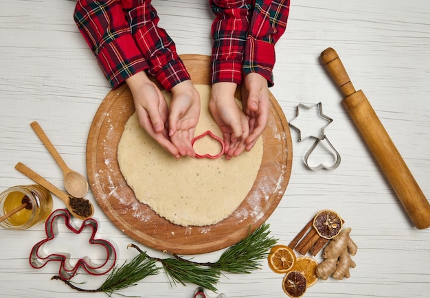 Postura plana das mãos de crianças, cortando biscoitos de massa de pão de gengibre crua. tradições de celebração de natal e ano novo. preparação de comida tradicional festiva, culinária familiar.