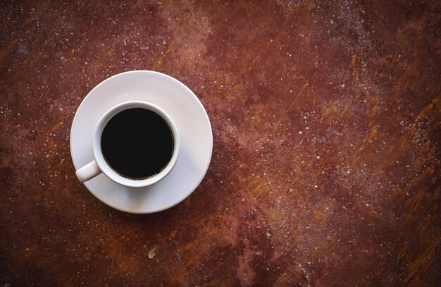 Postura plana de café americano quente em xícara de café branco sobre fundo marrom