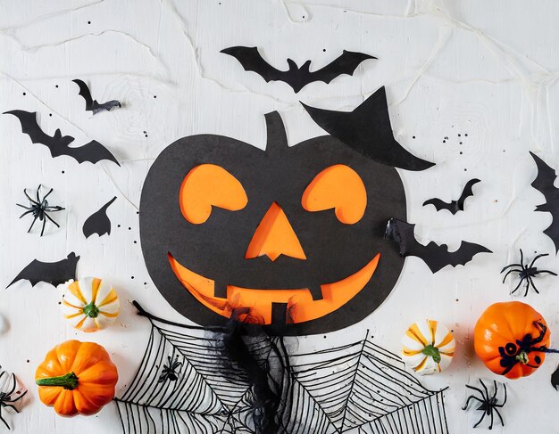 Foto postura plana de halloween com máscara de abóbora, chapéu de bruxa, morcegos voadores, teia decorativa e fantasma assustador