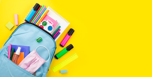 Postura plana de itens essenciais da escola com mochila e lápis de cor