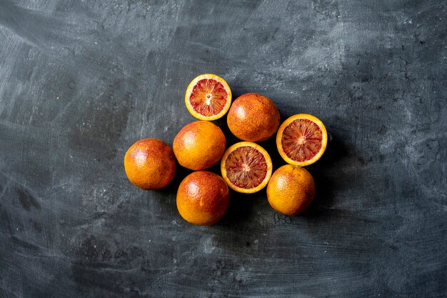 Postura plana de laranjas exóticas em fatias vermelhas, comida escura em superfícies pretas