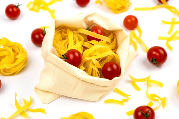 Postura plana de massa italiana com tomate cereja Tagliatelle ou Fettuccine em um saco de tecido