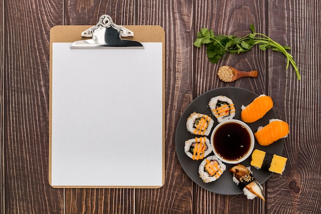 Postura plana de menu em branco com sushi na superfície de madeira