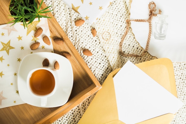 Postura plana de outono com chá no presente de bandeja de madeira e carta em envelope dourado