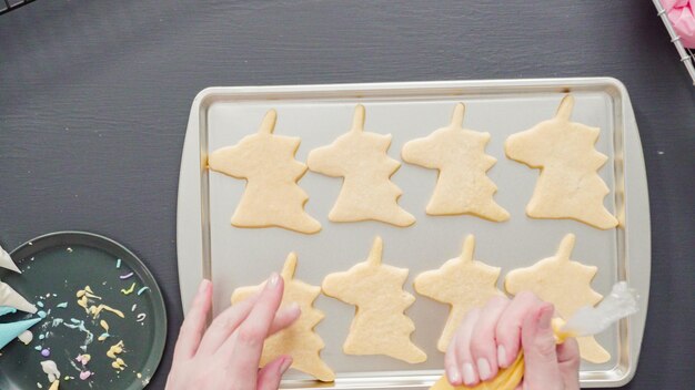 Postura plana. Decorando biscoitos de açúcar de unicórnio com glacê real multicolorido.