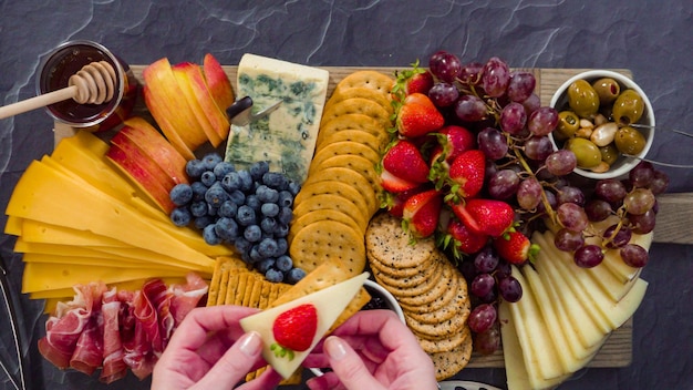 Postura plana. Disposição de queijos gourmet, crakers e frutas em uma tábua para uma grande tábua de queijos.