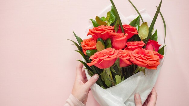 Postura plana. Florista embrulhando rosas vermelhas em um lindo buquê.