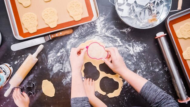 Postura plana. Mãe e filha assando biscoitos de caveira de açúcar para o feriado de Dia de los Muertos.