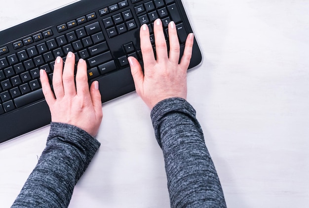 Foto postura plana. mulher digitando no teclado de computador preto.