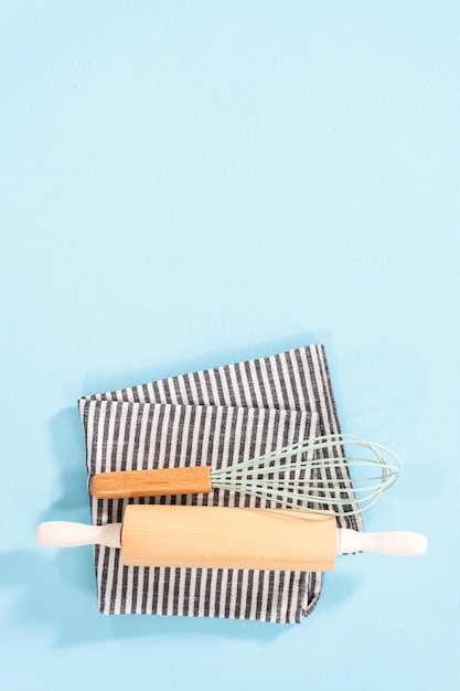 Postura plana. Novos utensílios de cozinha de silicone azul com alças de madeira em um fundo azul.