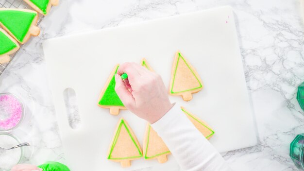 Postura plana. Passo a passo. Biscoitos de açúcar em forma de árvore de Natal de confeiteiro com glacê real verde.