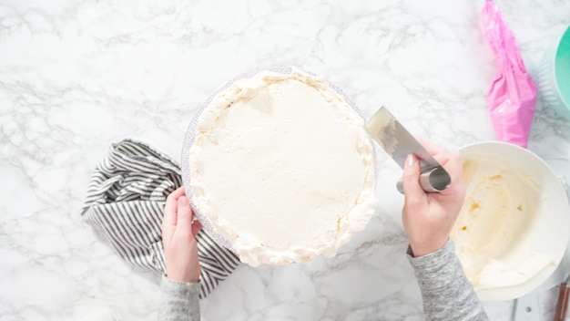 Postura plana. Passo a passo. Bolo de funfetti redondo com cobertura de creme de manteiga italiano branco.