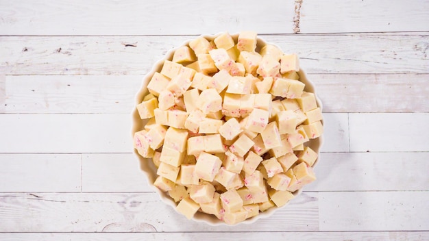 Postura plana. passo a passo. candy cane fudge cortado em pequenos cubos em uma travessa branca.