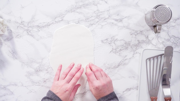 Postura plana. Passo a passo. Cortar flocos de neve com cortadores de biscoito de fondant branco em um balcão de mármore.