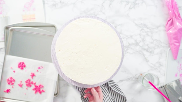 Postura plana. passo a passo. decorando o bolo de funfetti redondo com flocos de neve de fondant rosa e branco.