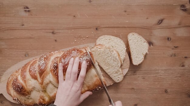 Postura plana. Passo a passo. Fatiar o pão shalah recém-assado com sementes de gergelim e papoula.