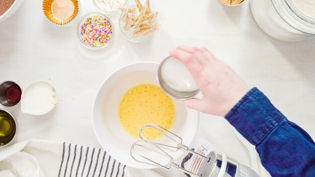 Postura plana. passo a passo. misturar os ingredientes em uma tigela branca para fazer cupcakes de chocolate unicórnio com cobertura de creme de manteiga.