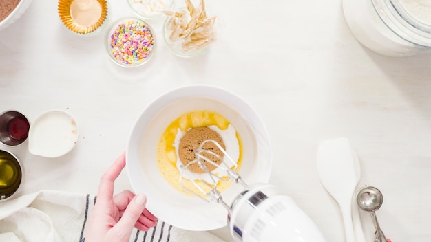 Postura plana. Passo a passo. Misturar os ingredientes em uma tigela branca para fazer cupcakes de chocolate unicórnio com cobertura de creme de manteiga.