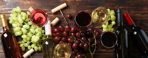 Postura plana. Uvas, saca-rolhas, garrafas e copos com vinho na madeira