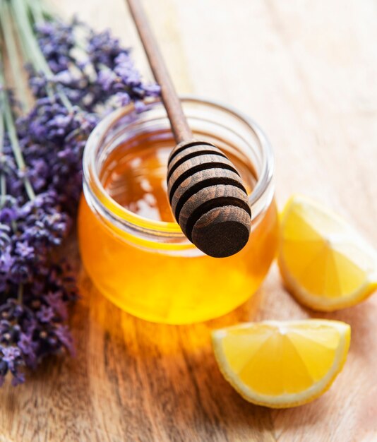 Pote com mel e flores frescas de lavanda em um fundo de madeira